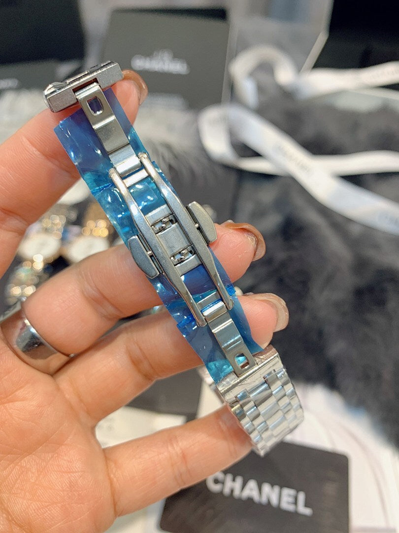 Chanel wristwatch close-up with silver links and blue rectangular detail