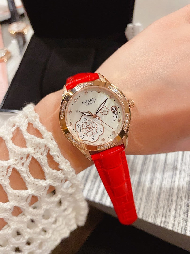 Chanel watch with red leather strap, round gold-tone case and floral dial close-up