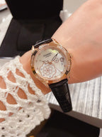 Chanel watch with black leather strap, round gold-tone case and floral dial
