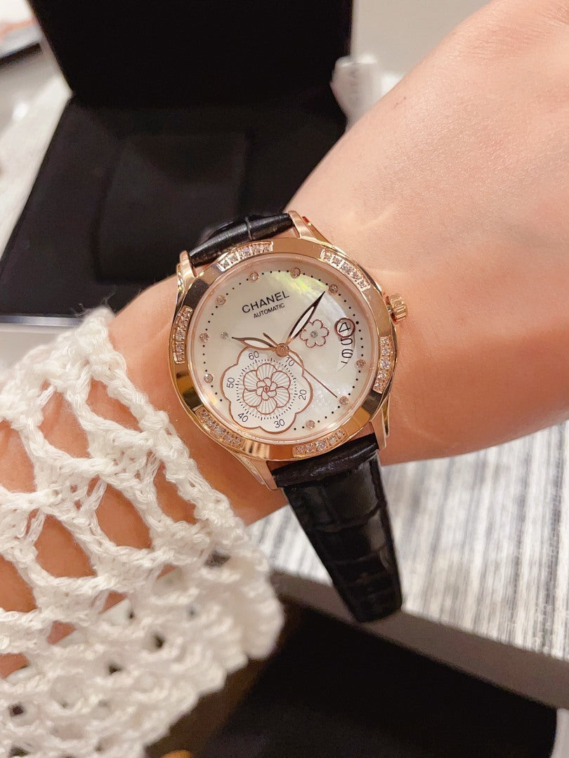 Chanel watch with black leather strap, round gold-tone case and floral dial