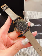 Chanel watch back on beige leather strap, gold-tone case with engraved text