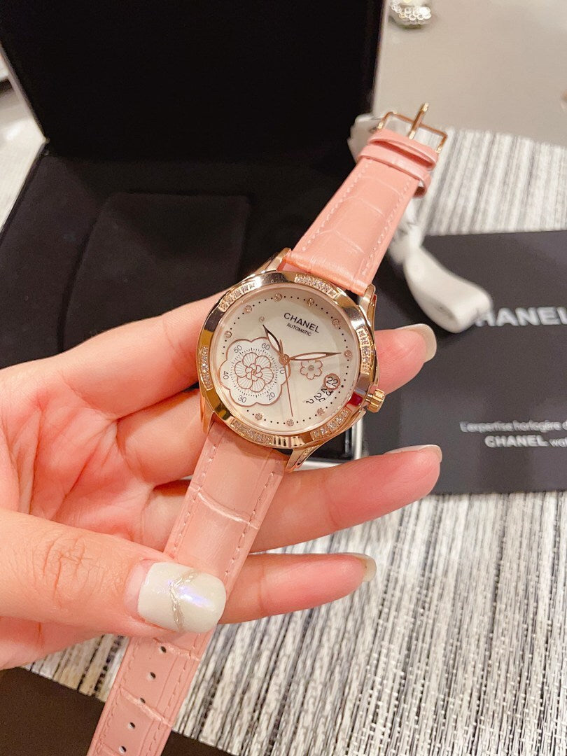 Chanel watch with pink leather strap, gold-tone case and floral dial, held in hand