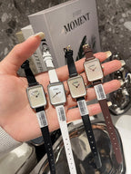 Chanel square-faced wristwatches in black, white, brown, and light straps in hand