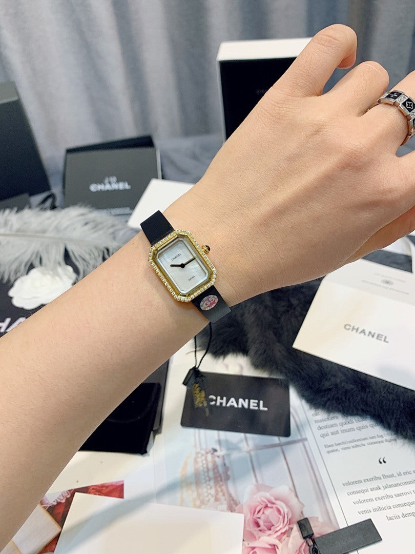 Gold-toned square wristwatch with light dial and black leather strap on wrist