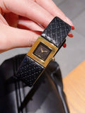 Chanel watch with black leather strap and gold-tone square dial on a hand