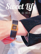 Chanel watch with black leather strap and gold-tone square dial worn on wrist