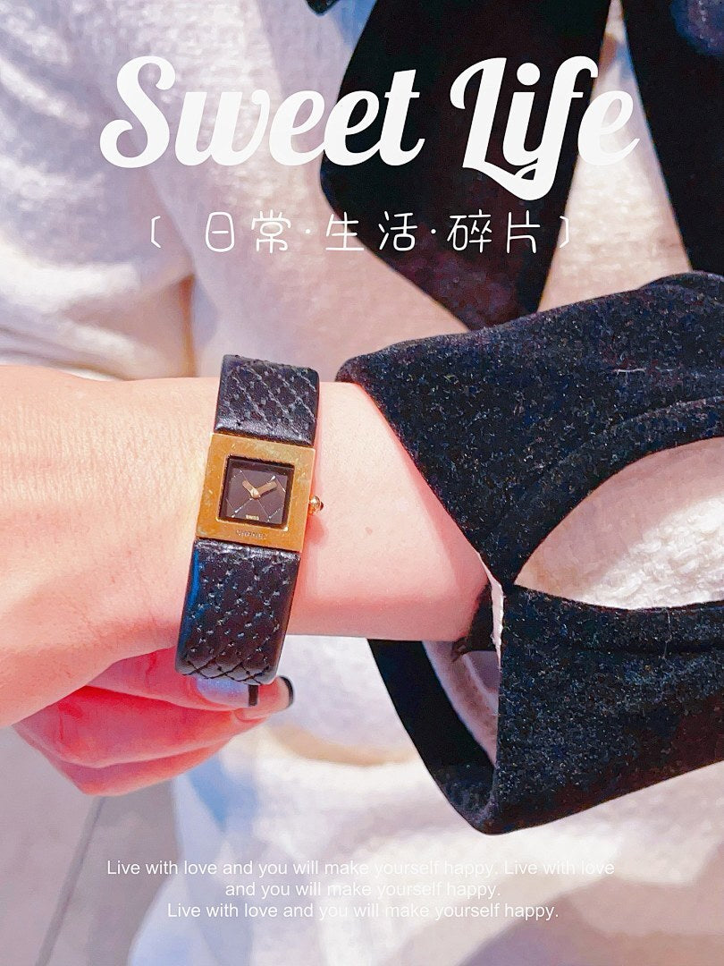 Chanel watch with black leather strap and gold-tone square dial worn on wrist
