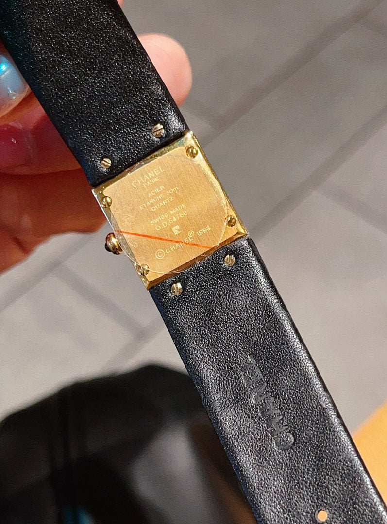 Chanel watch close-up with black textured leather strap and gold-tone case