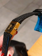 Chanel watch with black leather strap, gold-tone case, and side knob detail
