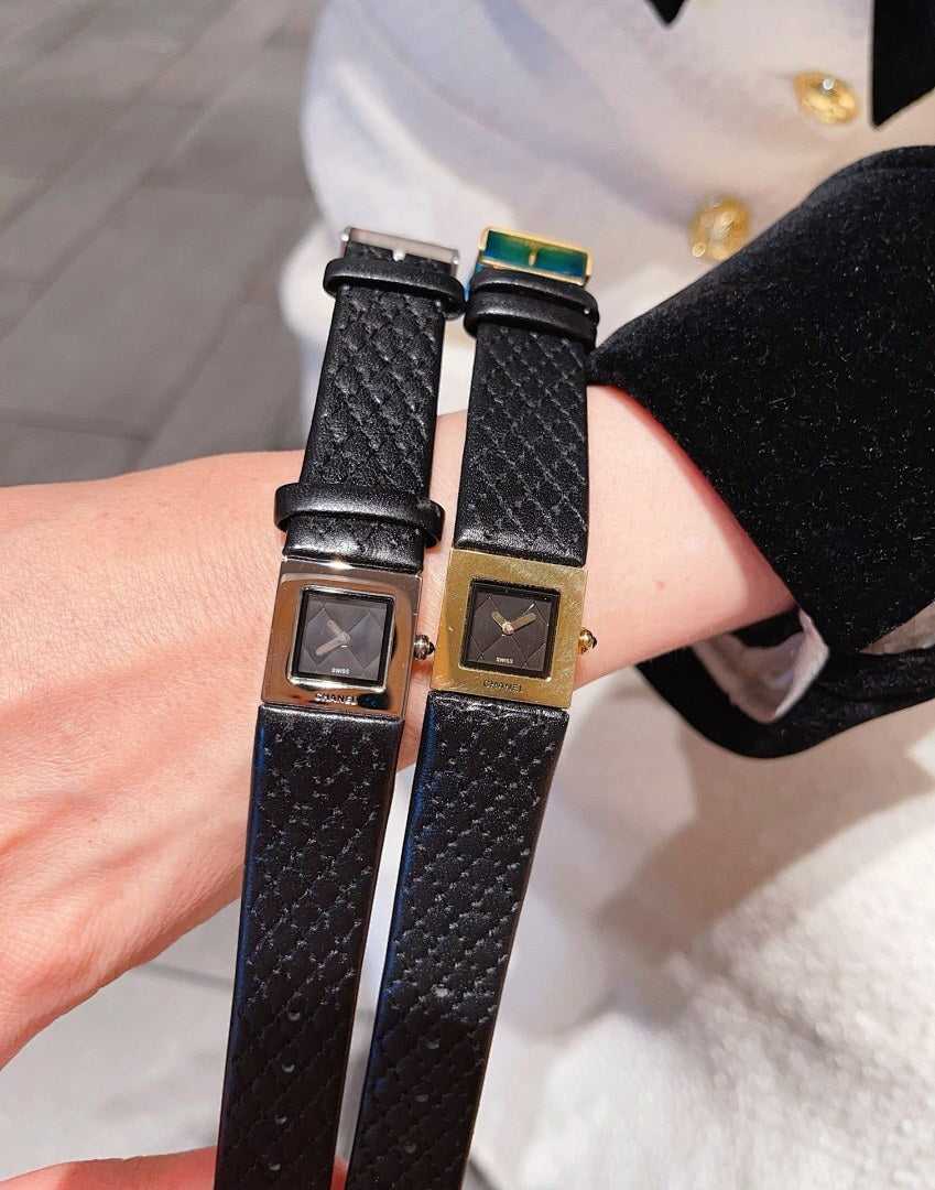 Two Chanel watches with black leather straps and square dials, gold and silver tones