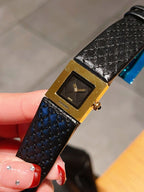 Chanel watch close-up with black textured leather strap and gold-tone square dial