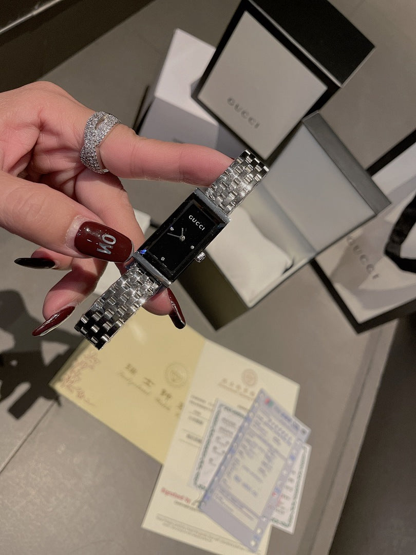 Chanel wristwatch held in hand, silver metal bracelet and black dial