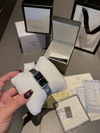 Chanel wristwatch with silver link bracelet on white cushion, black dial