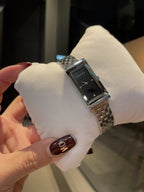 Chanel wristwatch on white pillow, silver metal bracelet with black dial