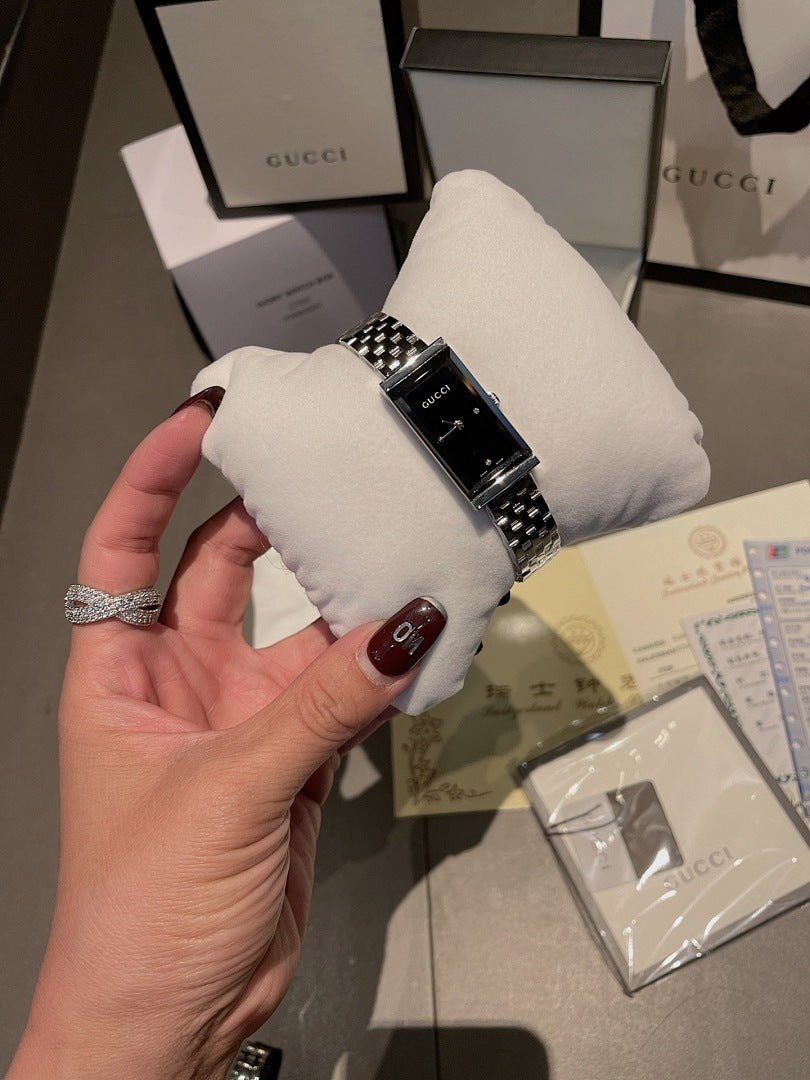 Chanel wristwatch on white cushion, silver metal bracelet with black face