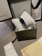 Chanel wristwatch on white cushion in display box, silver bracelet, black dial