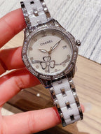 Chanel wristwatch with a white floral dial, diamond-look bezel, and silver metal link band.