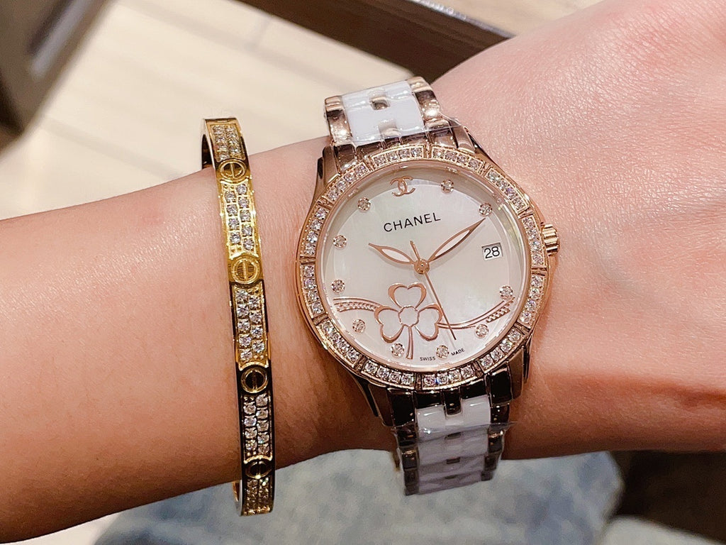 Chanel wristwatch with white floral dial, rose gold tone bezel, and silver metal link strap.