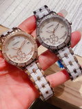 Pair of Chanel wristwatches with jeweled bezels and metal link straps, white floral dials.