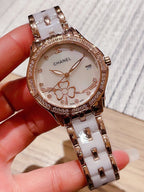 Chanel wristwatch with white floral dial, jeweled bezel, and silver metal link band.