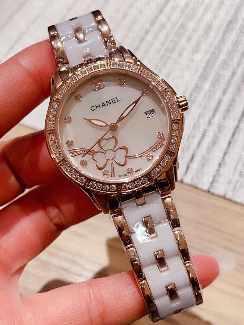 Chanel wristwatch with white floral dial, jeweled bezel, and silver metal link band.