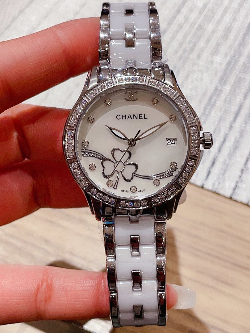 Chanel wristwatch with white floral dial, diamond-look bezel, and silver metal link bracelet.