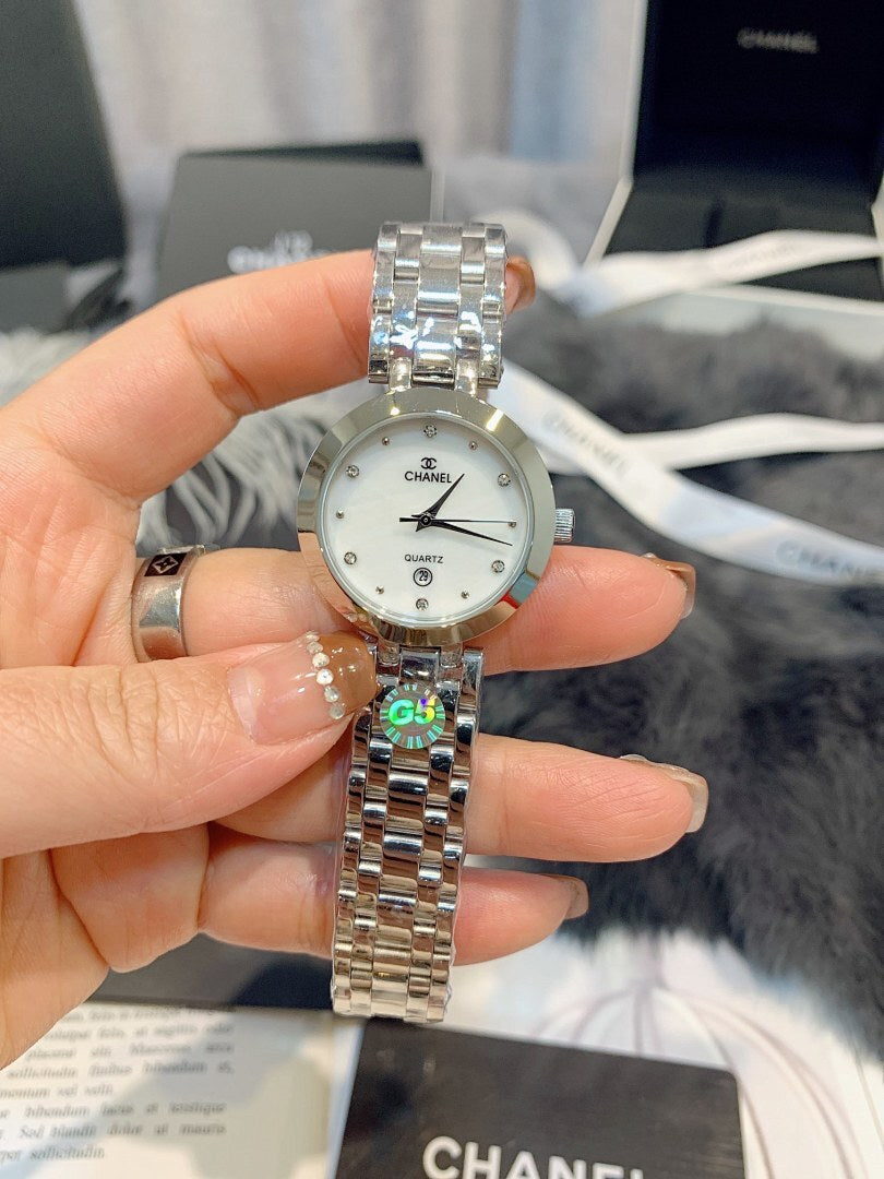 Chanel watch held up, round silver dial, gold-tone metal link bracelet