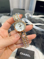 Chanel watch held in hand, round silver dial with two-tone gold and silver bracelet