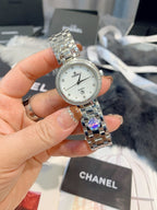 Chanel watch close-up held in hand, round silver dial and silver-tone metal bracelet