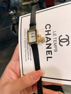 Chanel watch with dark dial and gold-tone case on black leather strap