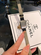 Chanel watch on black leather strap with gold-tone case and certificate card