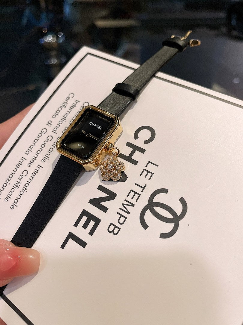 Chanel watch with dark dial, gold-tone case, and black leather strap on card