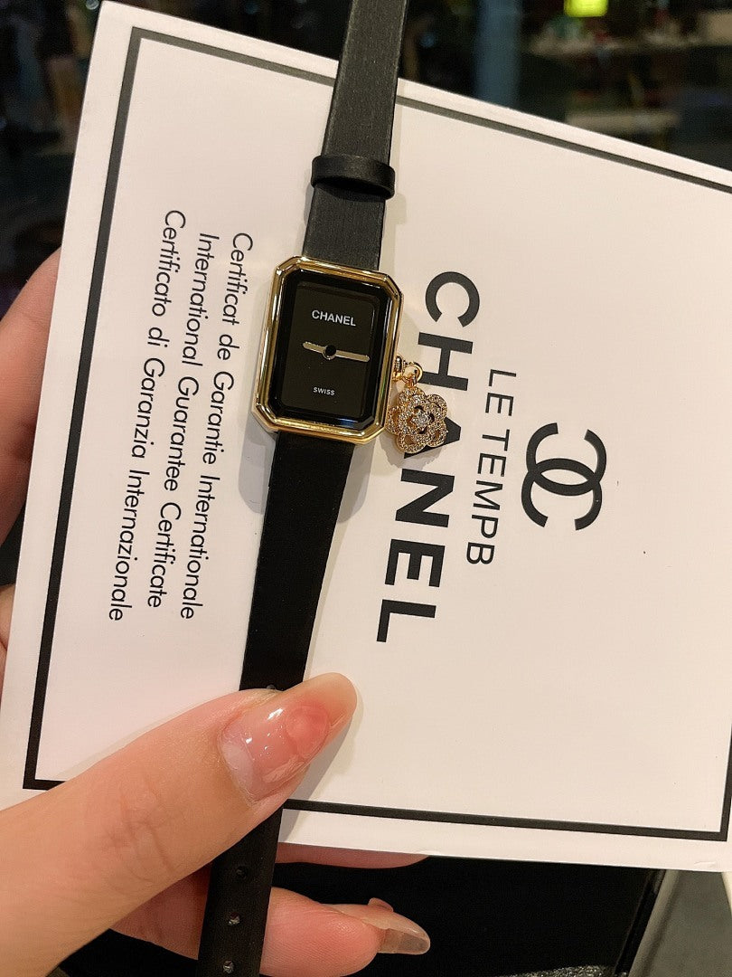 Chanel watch with dark dial, gold-tone case, and black leather strap on card