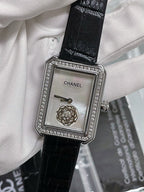 Square dial watch with black leather strap, rhinestone bezel, gold-toned emblem