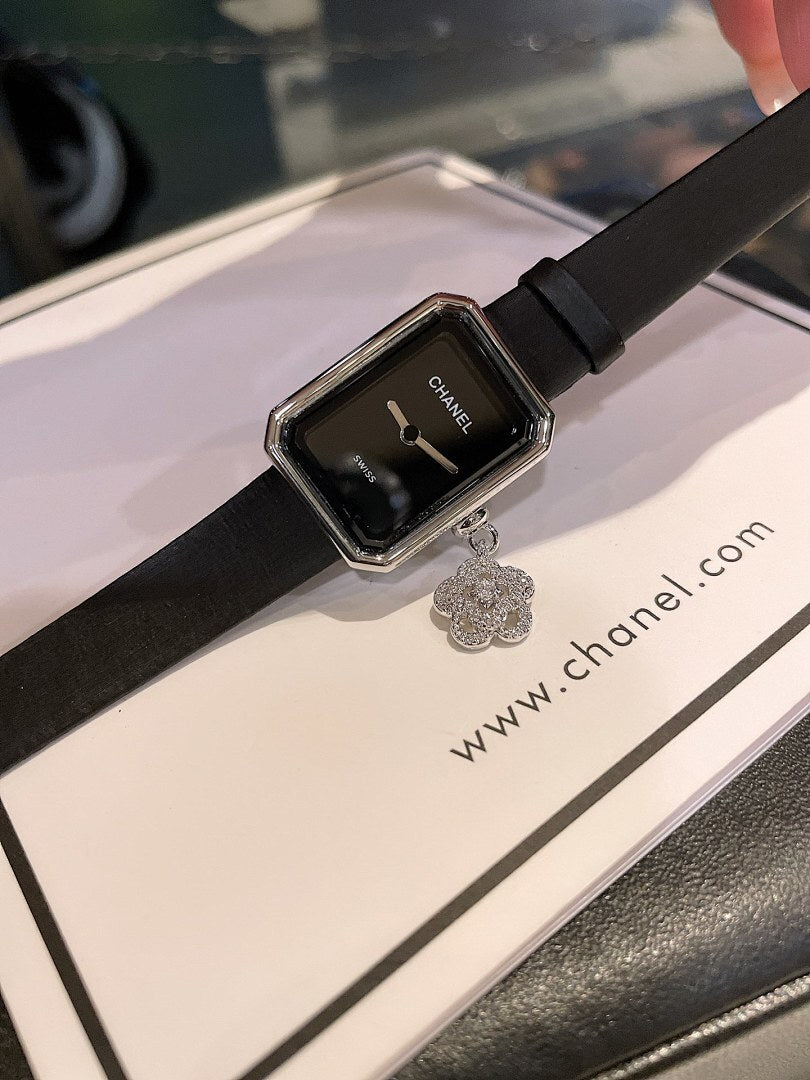 Chanel watch with black dial, rectangular silver case, and black leather strap