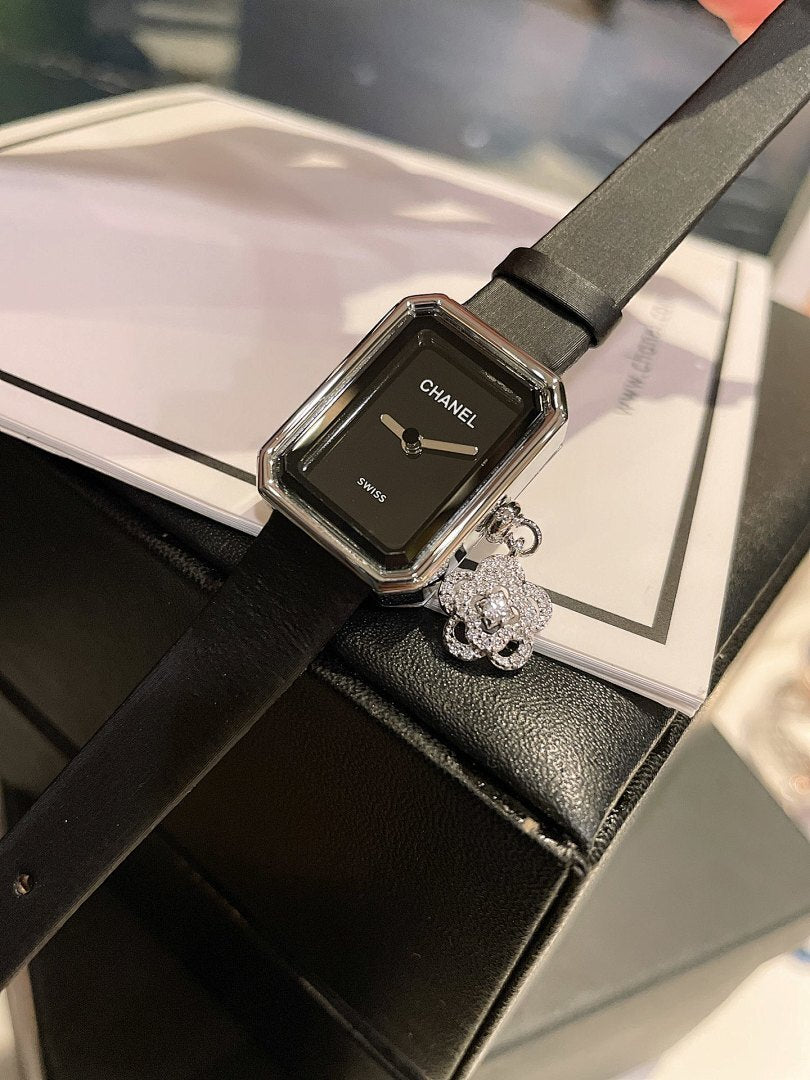 Chanel watch with black dial, rectangular silver case, and black leather strap
