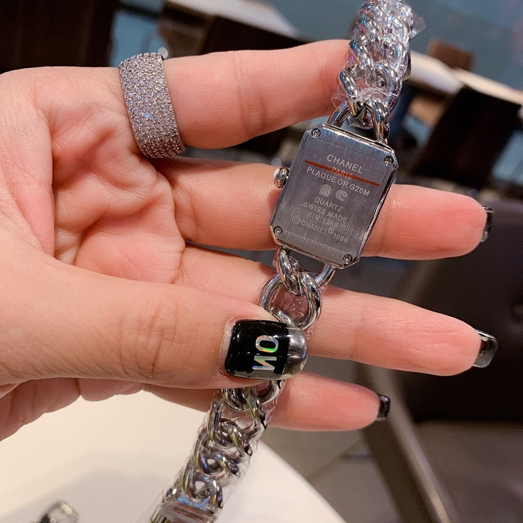 Chanel watch with silver chain and dark dial, held in hand
