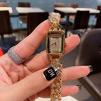 Chanel watch with gold case, gold chain, and rectangular dial held in hand