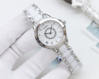 Silver analog wristwatch with white dial and metal link bracelet on glove