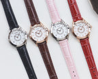 Set of four analog wristwatches with leather straps in black, brown, pink, and red