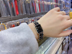 Black square dial wristwatch with silver chain bracelet on wrist