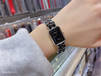 Black dial wristwatch with silver link bracelet, close-up