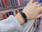 Square black dial wristwatch with silver link bracelet, angled view