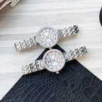 Pair of metal link CHANEL watches with jeweled bezels, white dials and blue/red accents