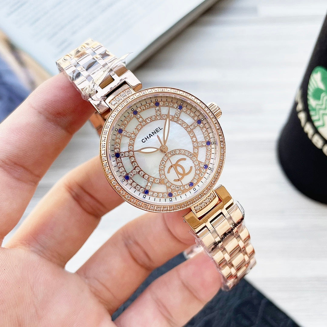 Two-tone CHANEL round watch with jeweled bezel, white dial with blue markers and metal bracelet