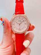 Chanel watch with red strap and rose-gold bezel, round white dial close-up