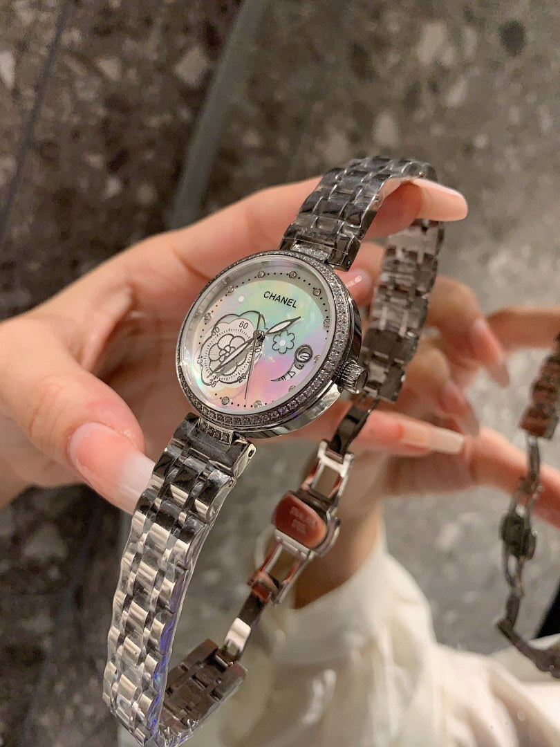 Chanel round wristwatch with silver-tone metal bracelet and white dial, angled view in hand