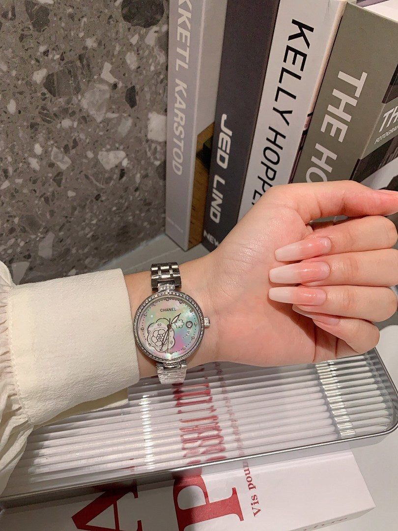 Chanel round wristwatch on wrist with silver-tone metal bracelet and light-colored dial, hand holding