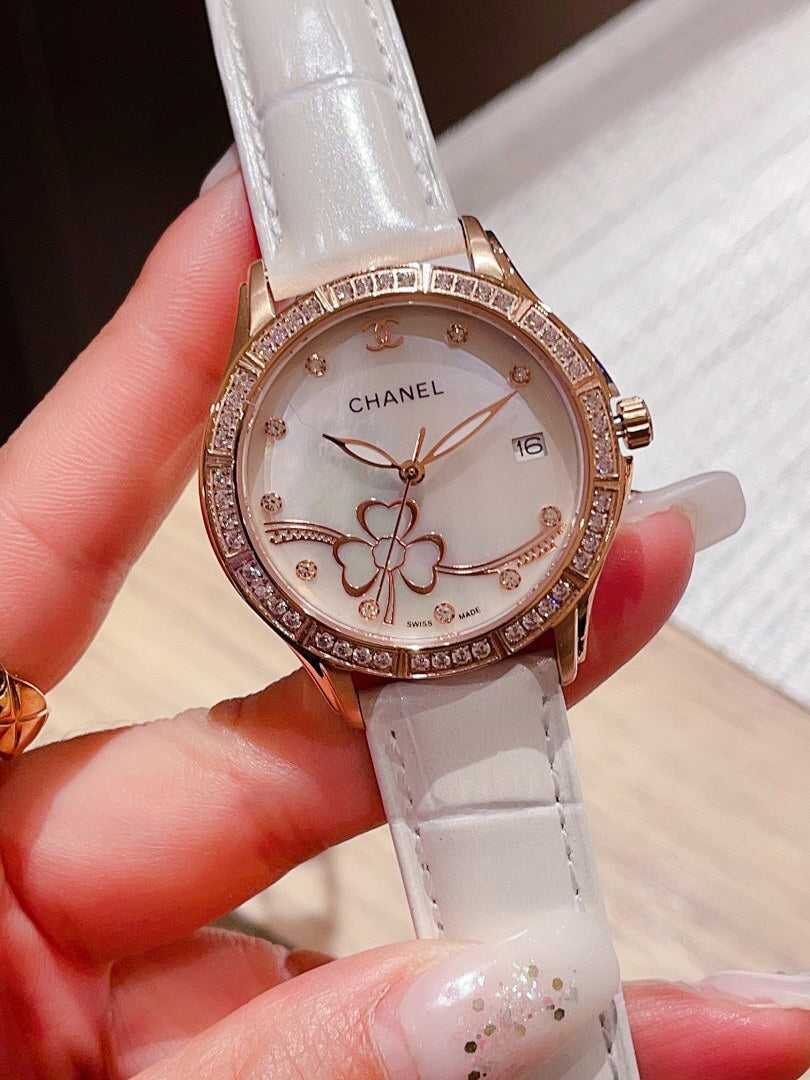 Chanel watch with jeweled bezel, white leather strap, round white floral dial.