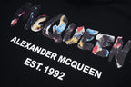 Black pullover hoodie close-up: multicolor “Alexander McQueen EST. 1992” graphic